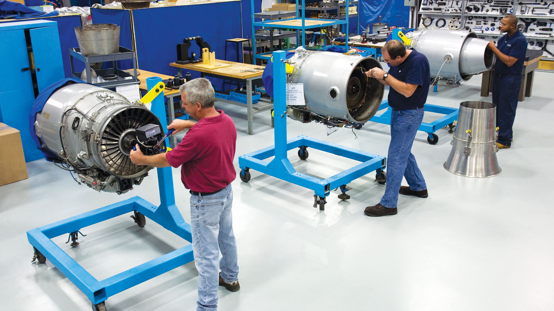 Three workers working on engines.